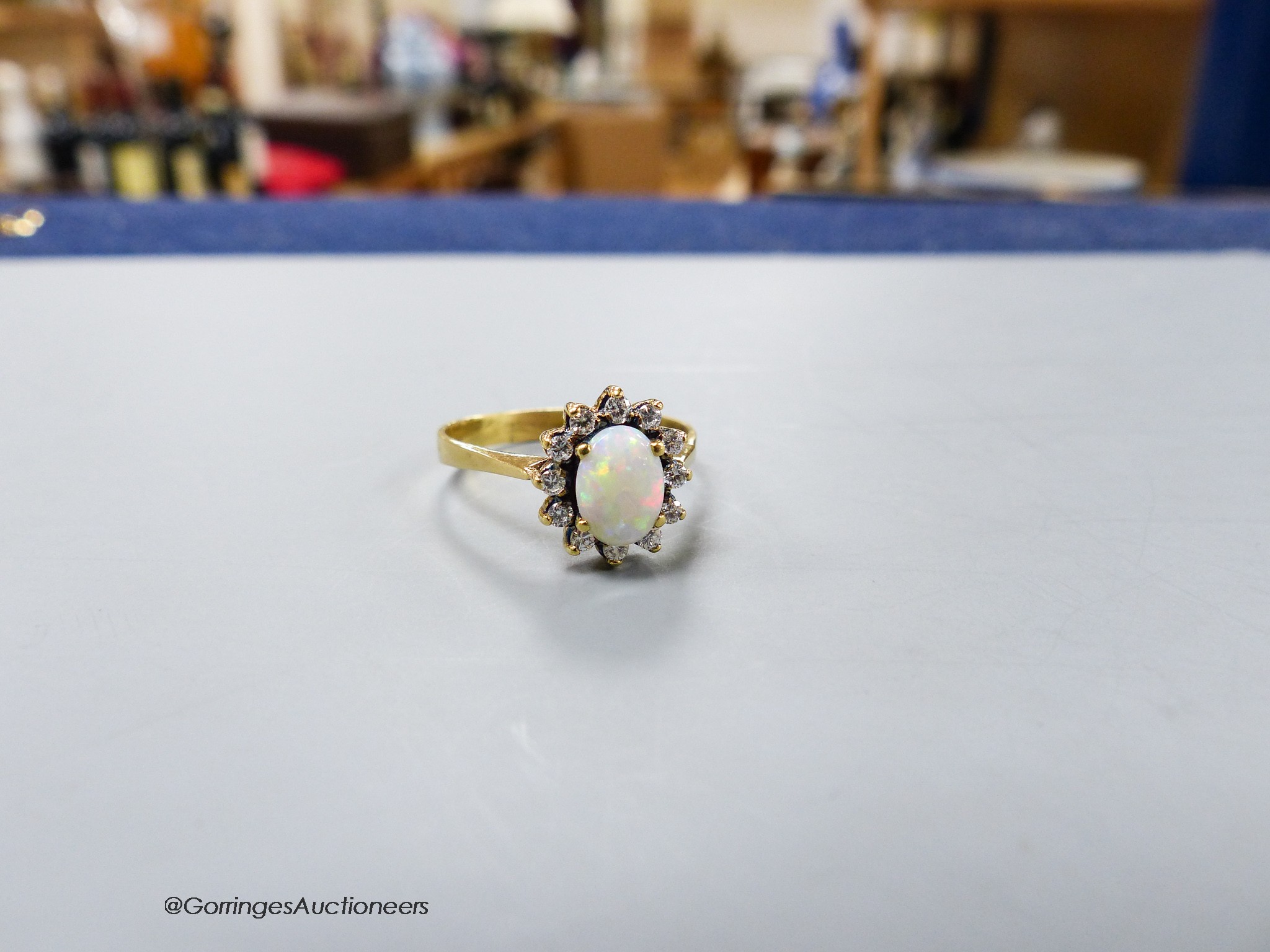 A modern yellow metal, white opal and diamond set oval cluster ring, size S, gross 4 grams.